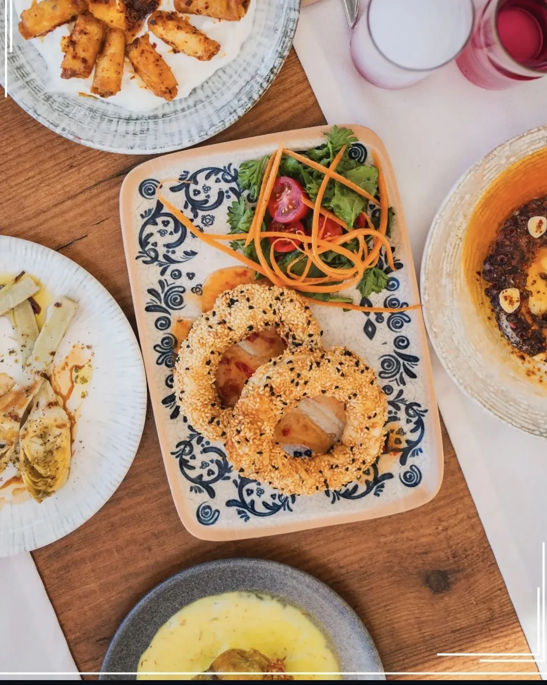 Ahşap masada mezeler, salata ve levrek simit